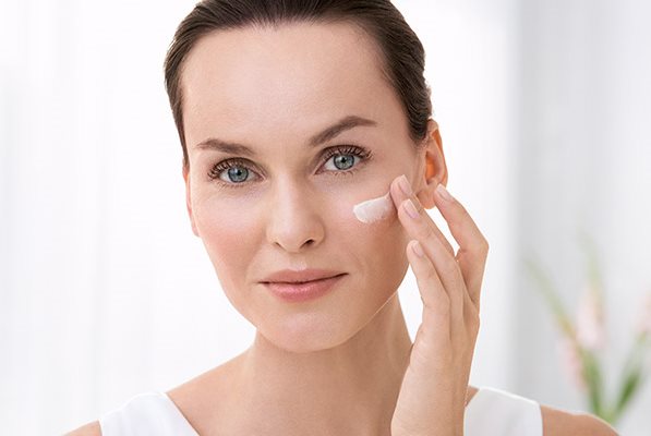 žena aplikující si krém na obličej