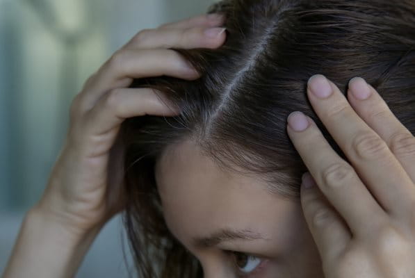 Frau betrachtet Ihre Haare im Spiegel